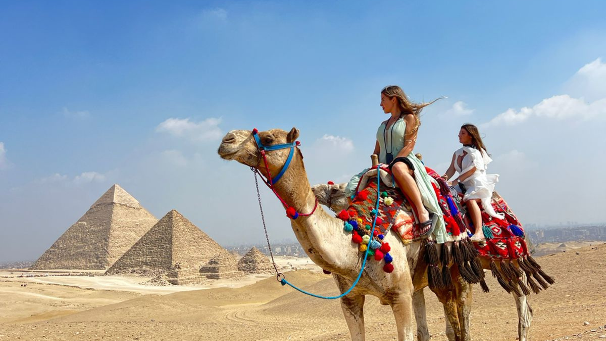 Tourists riding camels in front of the Great Pyramids of Giza, Egypt
