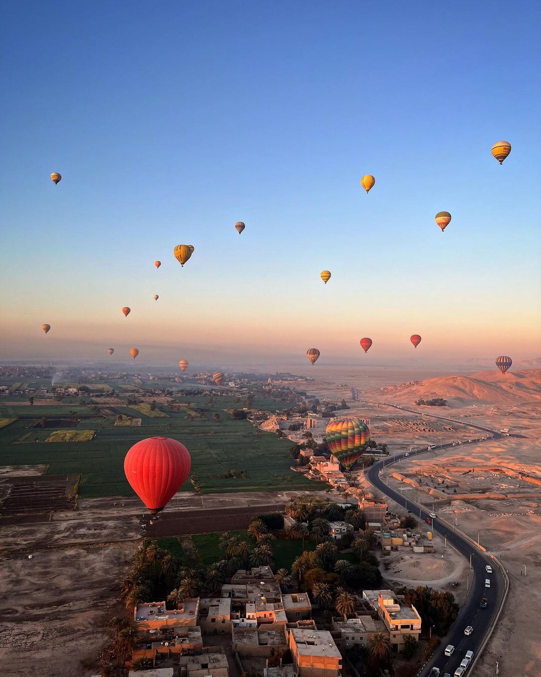 Dozens of hot air balloons floating over the Valley of the Kings at sunrise, Luxor, Egypt