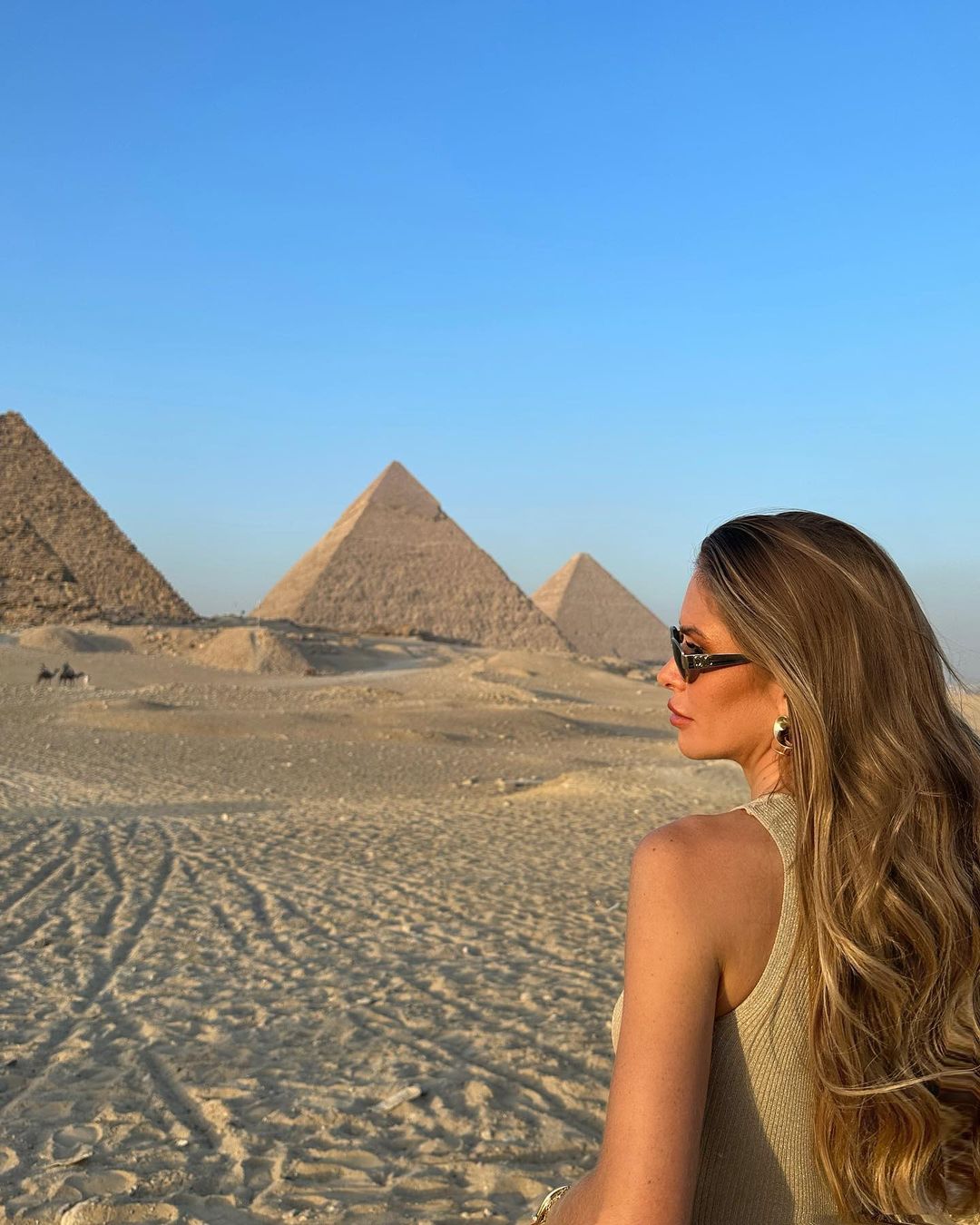 Woman gazing at all three Great Pyramids of Giza at golden hour, Egypt